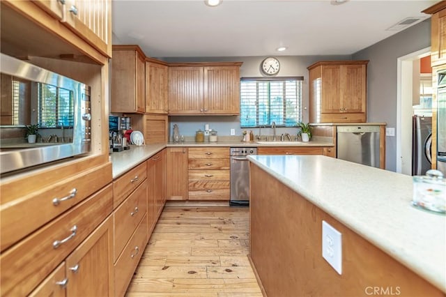 kitchen featuring stainless steel appliances, recessed lighting, light countertops, light wood-style floors, and a sink