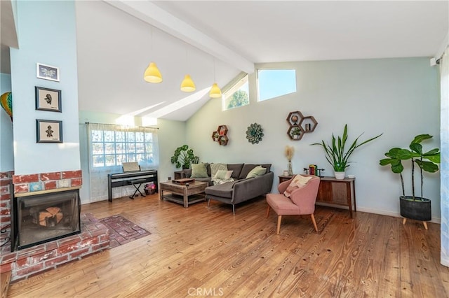 living area with high vaulted ceiling, wood finished floors, baseboards, a brick fireplace, and beamed ceiling