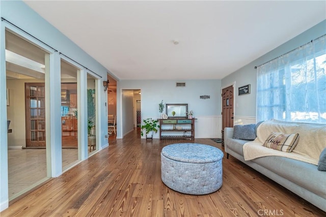 living area with wainscoting, visible vents, and wood finished floors