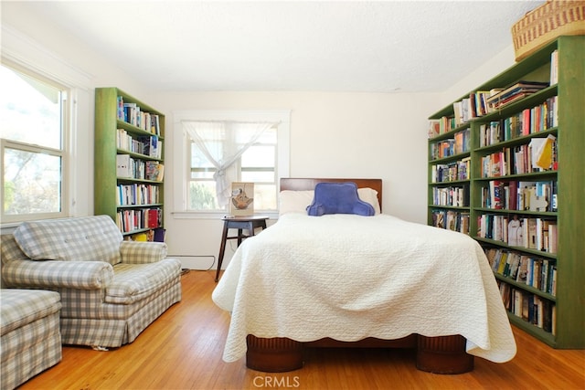 bedroom featuring a baseboard heating unit and wood-type flooring