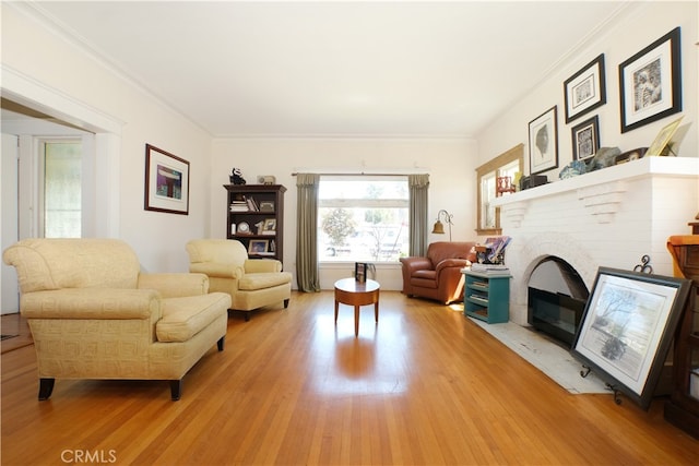 living room with wood-type flooring, a brick fireplace, and ornamental molding