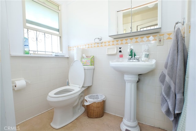 bathroom with toilet, tile walls, and sink