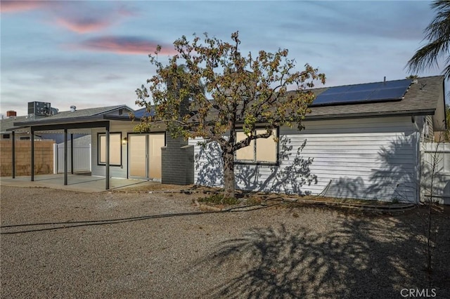 back house at dusk with a patio and solar panels