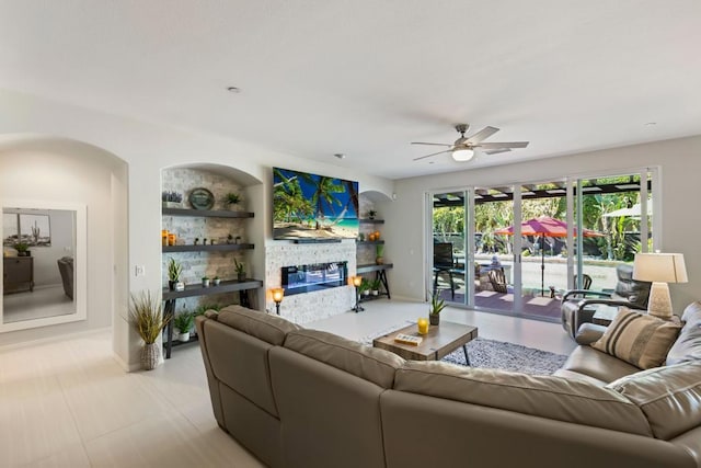 living room featuring ceiling fan, built in features, and a fireplace