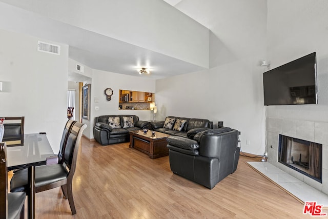 living room featuring light wood-type flooring and a tiled fireplace