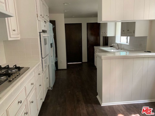 kitchen featuring sink, stainless steel gas cooktop, dark wood-type flooring, tile counters, and white cabinets