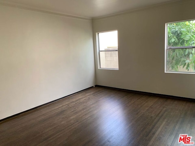 empty room with dark hardwood / wood-style flooring and crown molding