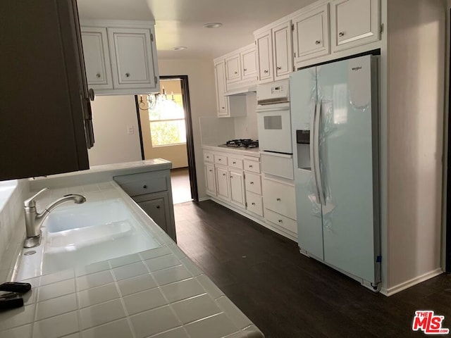 kitchen featuring white appliances, dark wood-type flooring, white cabinetry, sink, and tile countertops