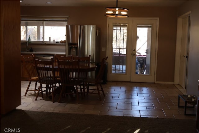 tiled dining space featuring french doors, sink, and an inviting chandelier