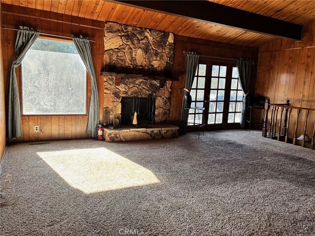 unfurnished living room featuring beam ceiling, carpet floors, and wooden walls