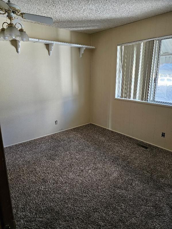 carpeted empty room with ceiling fan and a textured ceiling