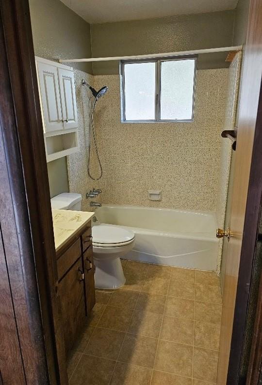 full bathroom featuring tiled shower / bath, tile patterned floors, toilet, and vanity