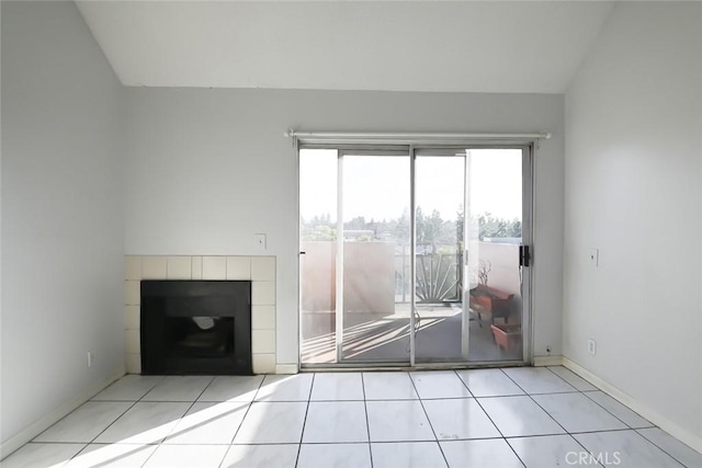 unfurnished living room with a tiled fireplace, light tile patterned floors, and vaulted ceiling