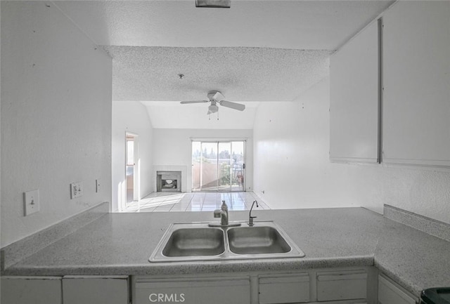 kitchen with vaulted ceiling, sink, ceiling fan, and a textured ceiling