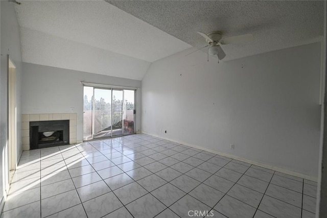 unfurnished living room featuring ceiling fan, a fireplace, a textured ceiling, light tile patterned flooring, and vaulted ceiling