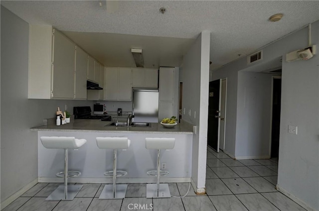 kitchen with white cabinetry, sink, range, and kitchen peninsula