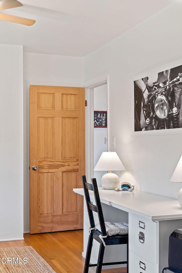 office space featuring light wood-type flooring, ceiling fan, and built in desk