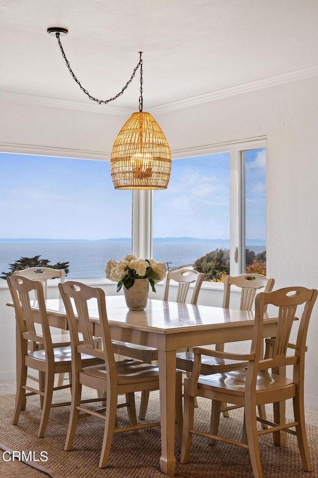 dining room featuring a water view, crown molding, and an inviting chandelier