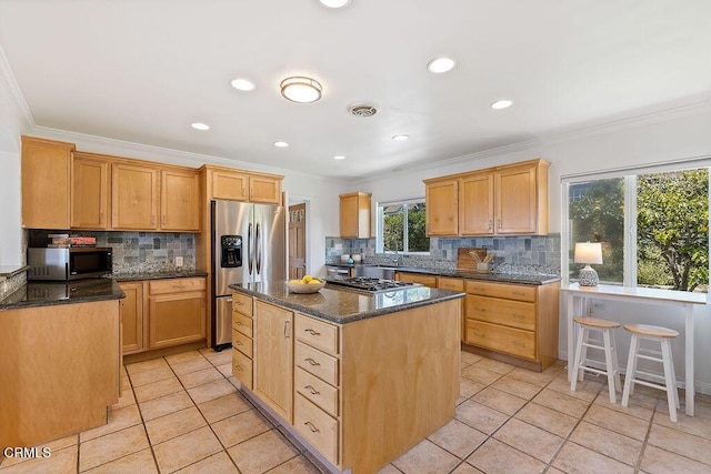 kitchen with appliances with stainless steel finishes, dark stone counters, ornamental molding, and a center island