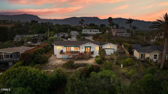 back house at dusk with a mountain view and a patio