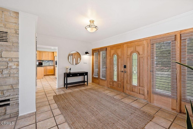 foyer with light tile patterned floors and crown molding