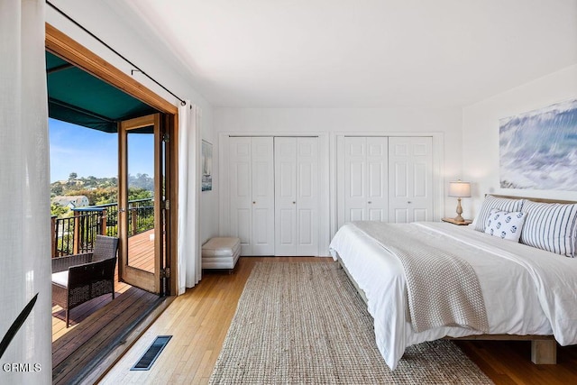 bedroom featuring two closets, light hardwood / wood-style flooring, and access to outside