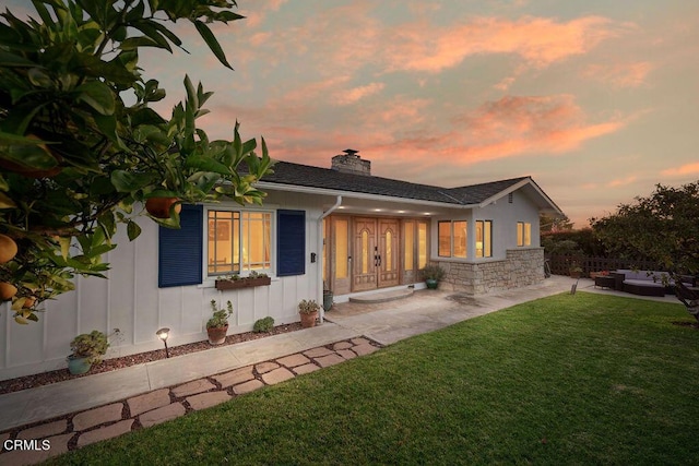 2335 Whitney Ave, Summerland, CA 93067 - back of property at dusk with a chimney, stone siding, an outdoor hangout area, a yard, and fence