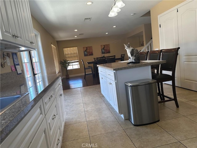 kitchen featuring light tile patterned flooring, a kitchen breakfast bar, white cabinetry, and a center island