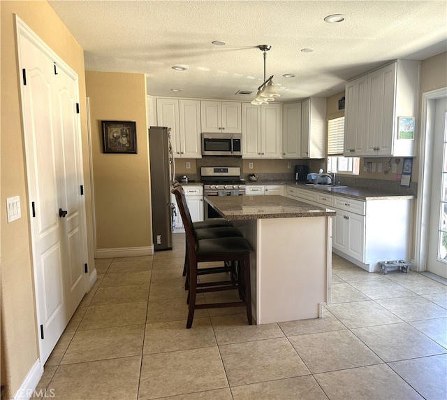 kitchen with a center island, white cabinetry, appliances with stainless steel finishes, a kitchen breakfast bar, and light tile patterned floors