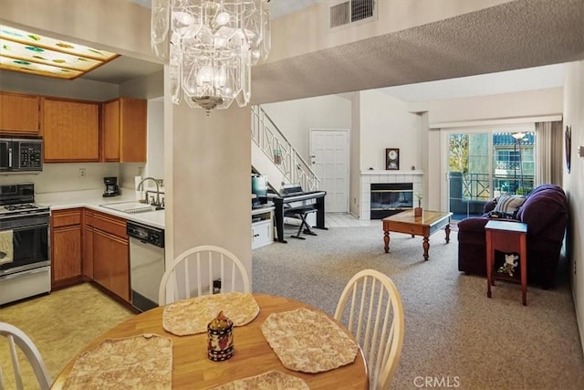 kitchen with range with gas cooktop, a fireplace, stainless steel dishwasher, sink, and an inviting chandelier