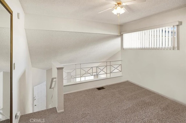 unfurnished room featuring ceiling fan, a textured ceiling, carpet flooring, and vaulted ceiling