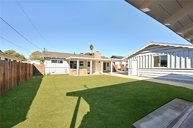 rear view of house featuring a hot tub, a lawn, and a patio