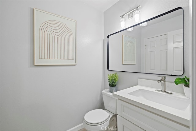 half bathroom featuring baseboards, toilet, and vanity