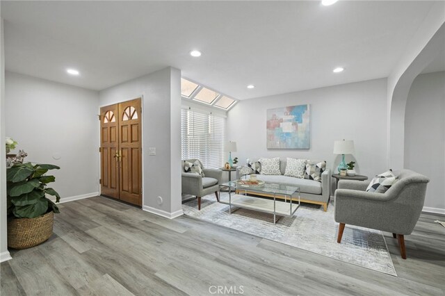 living room with arched walkways, baseboards, wood finished floors, and recessed lighting
