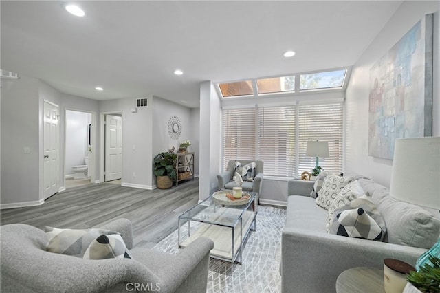 living area featuring baseboards, visible vents, wood finished floors, and recessed lighting