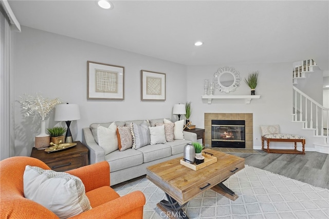 living room featuring a tiled fireplace and light wood-type flooring