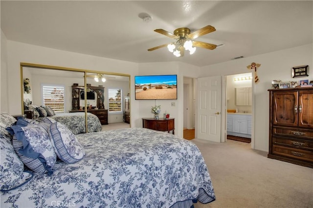 carpeted bedroom featuring ceiling fan, ensuite bathroom, and a closet