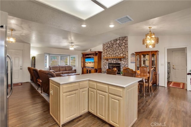 kitchen with kitchen peninsula, dark wood-type flooring, a fireplace, vaulted ceiling, and ceiling fan with notable chandelier