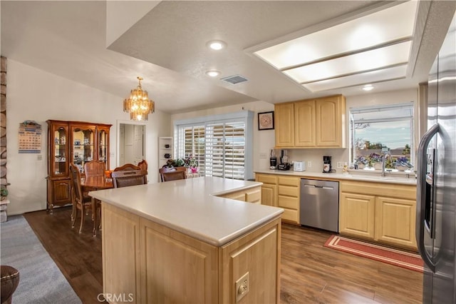 kitchen featuring appliances with stainless steel finishes, dark hardwood / wood-style floors, decorative light fixtures, light brown cabinetry, and a center island