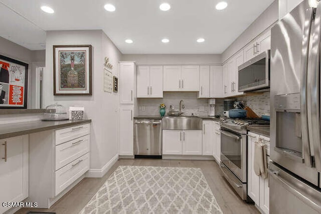 kitchen with white cabinets, decorative backsplash, appliances with stainless steel finishes, and sink