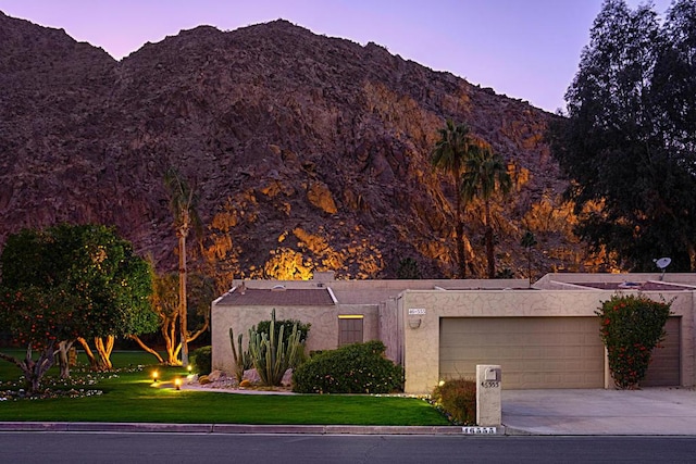 view of front of home featuring a garage, a mountain view, and a yard