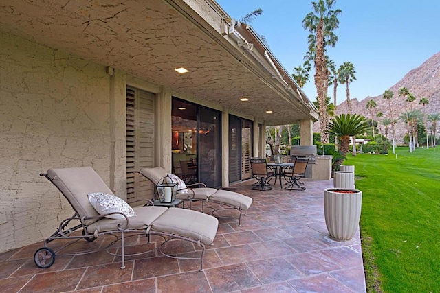 view of patio / terrace with exterior kitchen, a mountain view, and grilling area