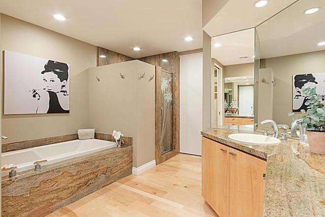 bathroom featuring hardwood / wood-style flooring, vanity, and separate shower and tub