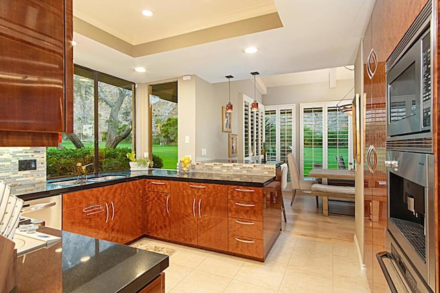 kitchen with kitchen peninsula, appliances with stainless steel finishes, backsplash, pendant lighting, and sink