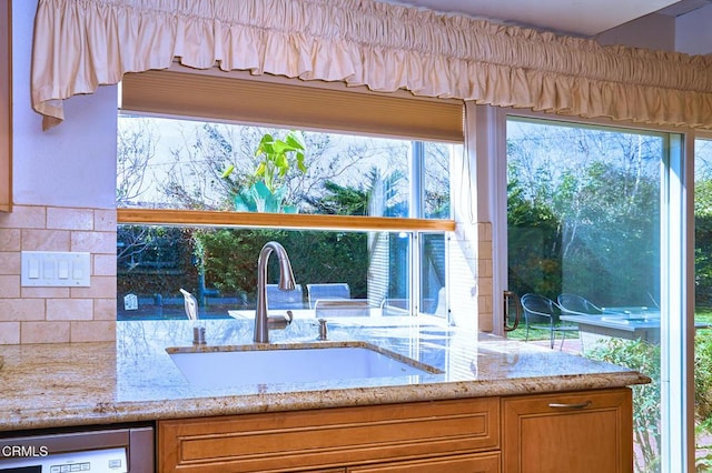 interior space featuring light stone counters, sink, and dishwashing machine