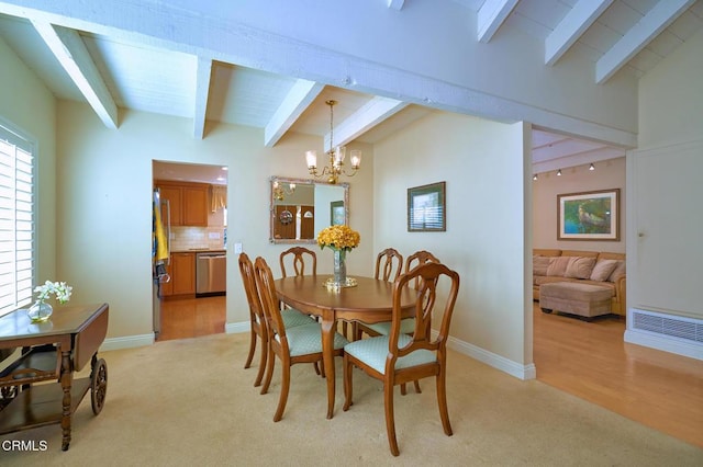 dining area featuring a chandelier, light colored carpet, and beam ceiling