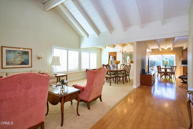 living room with beam ceiling, high vaulted ceiling, light hardwood / wood-style flooring, and a notable chandelier