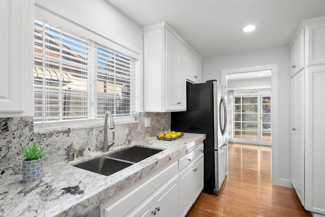 kitchen with light stone counters, sink, white cabinets, and tasteful backsplash