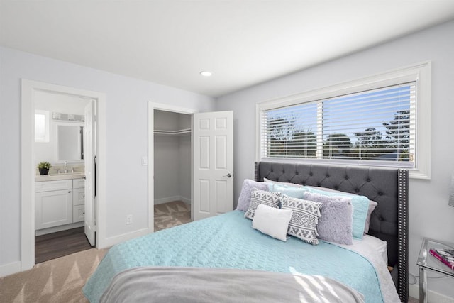 bedroom featuring carpet, sink, connected bathroom, a walk in closet, and a closet