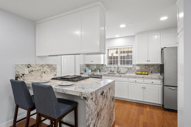 kitchen featuring appliances with stainless steel finishes, white cabinetry, sink, kitchen peninsula, and a breakfast bar area